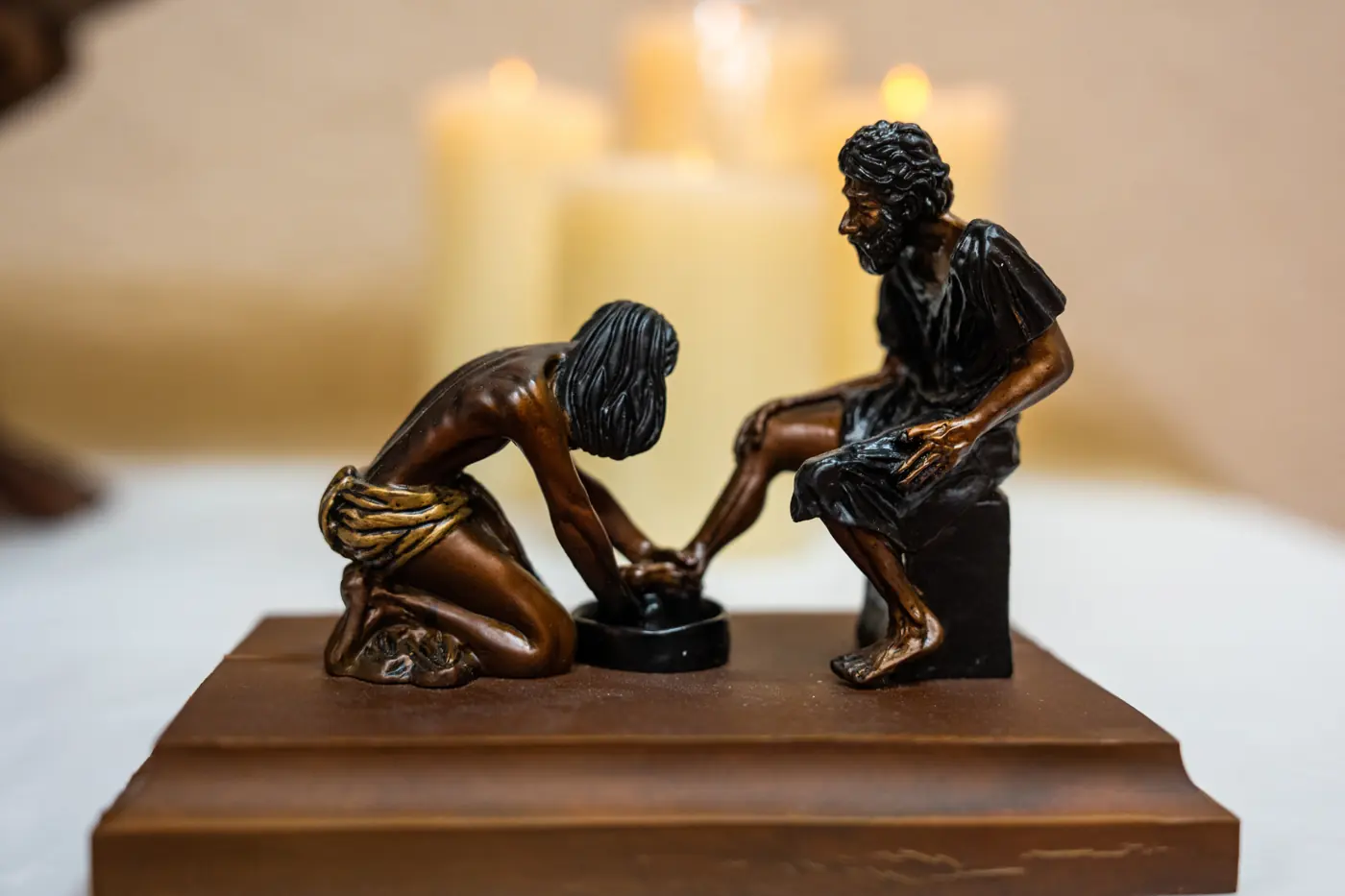 Candles beside a small sculpture of Jesus washing feet